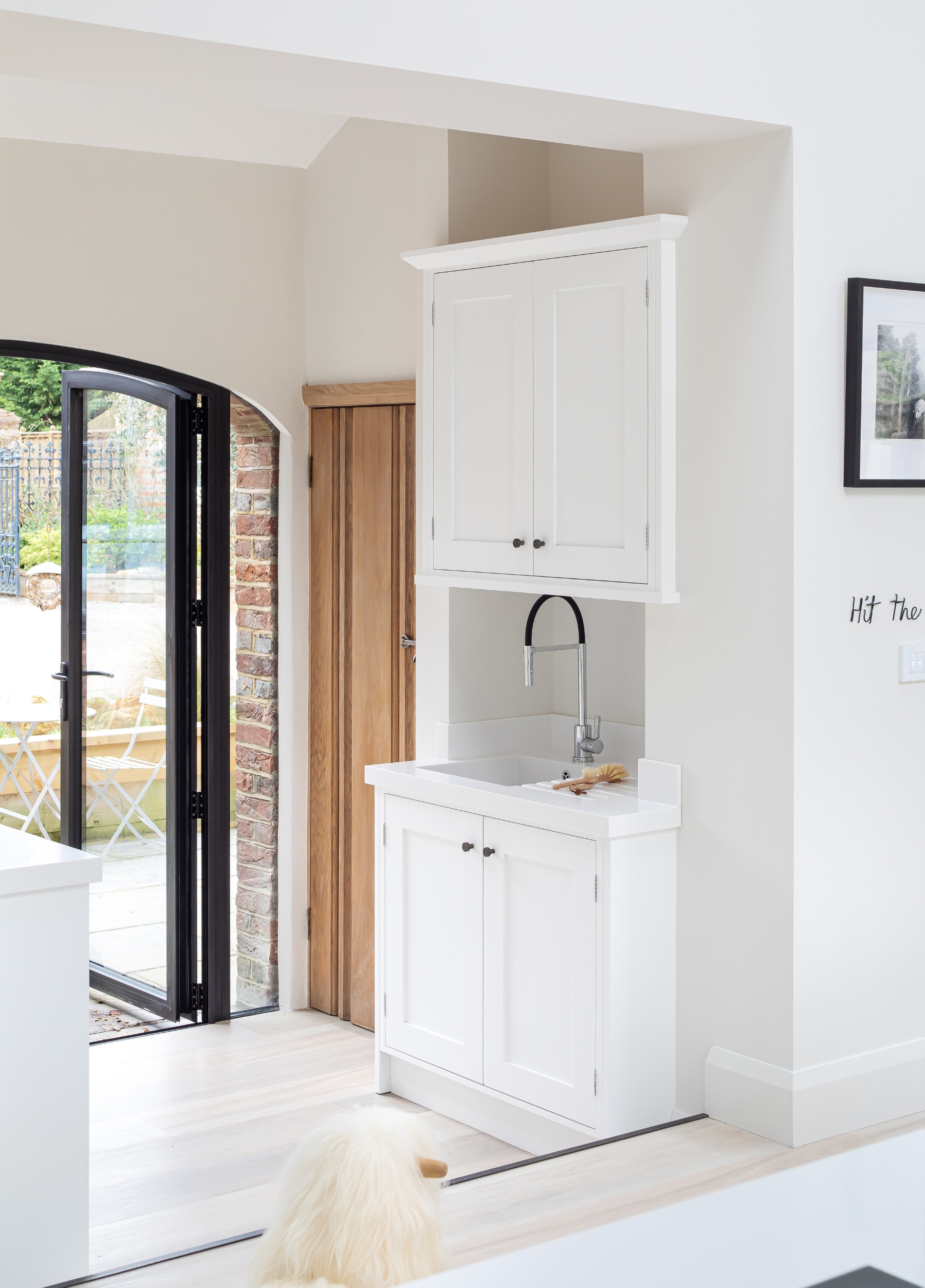 White shaker kitchen cabinets with utility sink and Crittall style double doors.